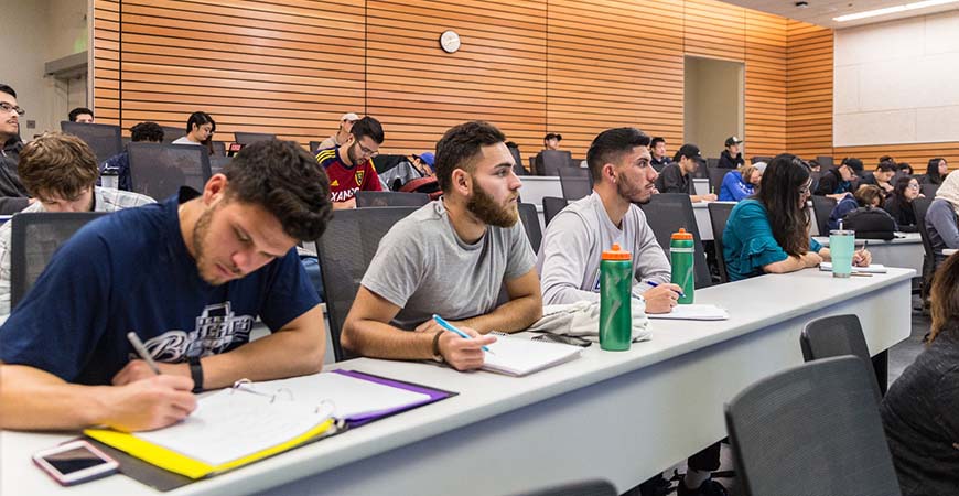 Students sit in a classroom while listening to a lecture. 