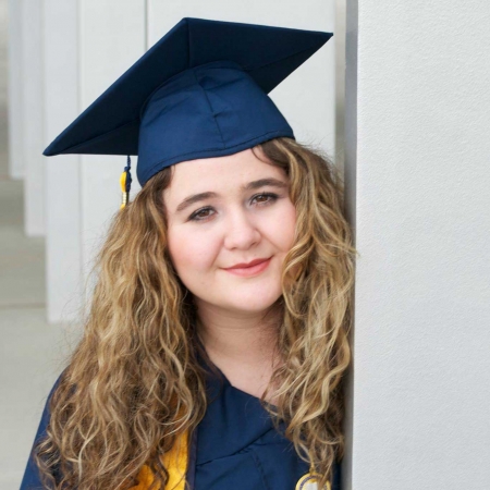 Young woman with long, light-brown hair in blue graduation cap.